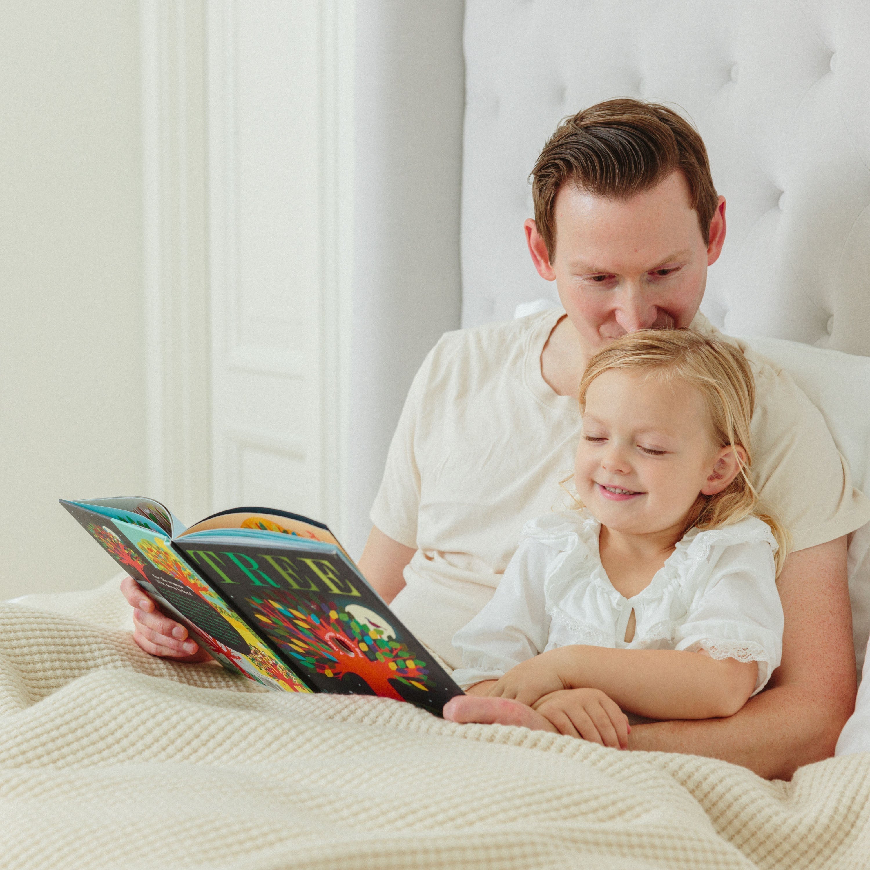 Dad and daughter reading a bedtime story with a cozy merino AU Baby adult blanket