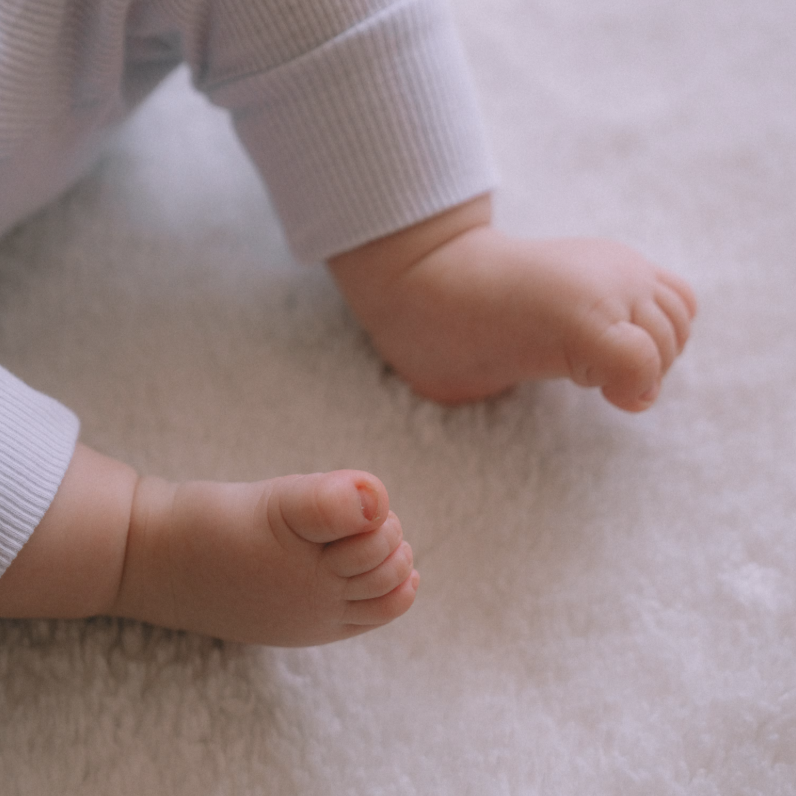 Close-up of a baby's bare feet resting on a soft, fleece-textured blanket.