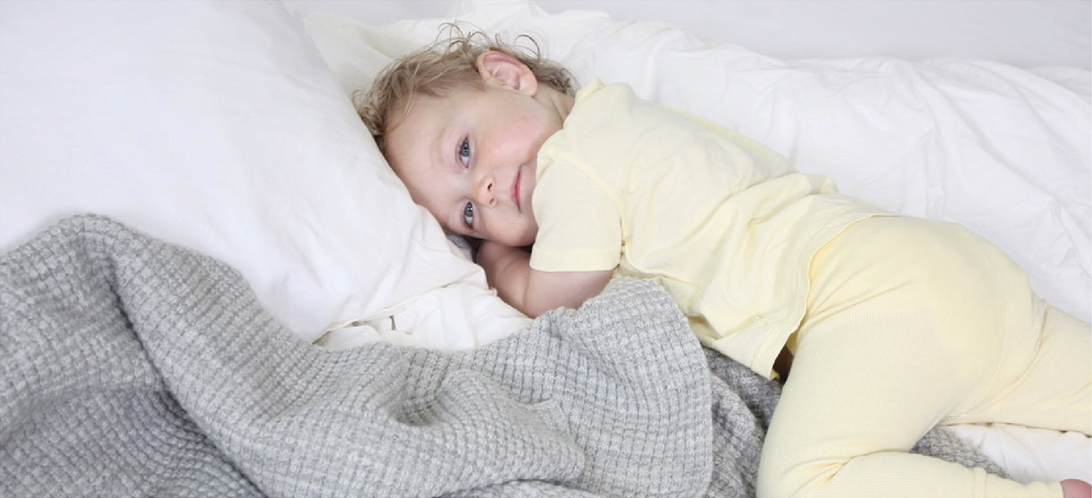 Toddler relaxing on a grey merino AU Baby Popcorn blanket.