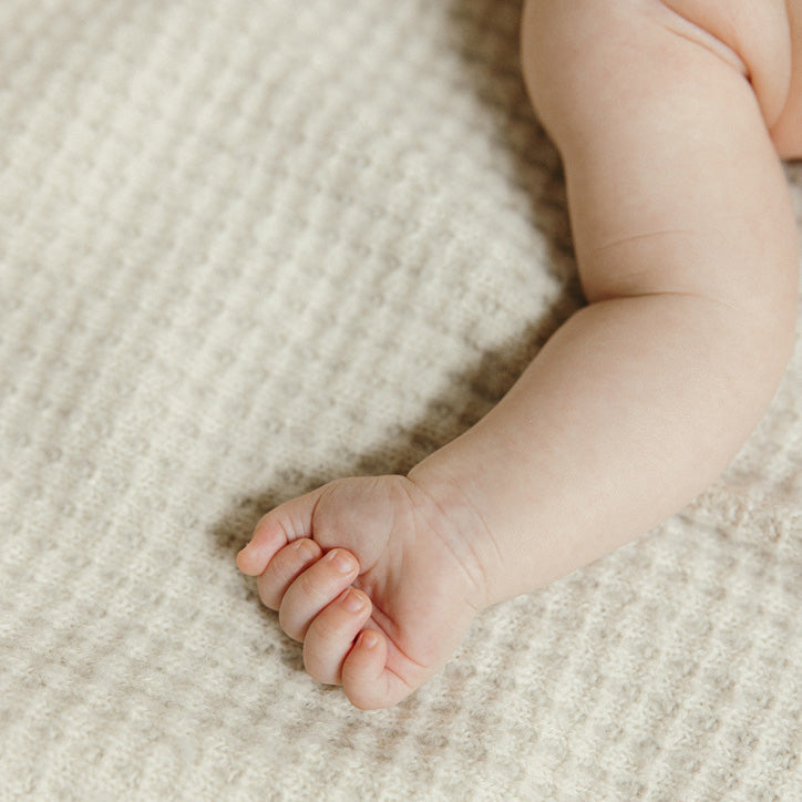 Baby's arm on AU Baby 100% merino FSA eligible blanket for eczema and insomnia