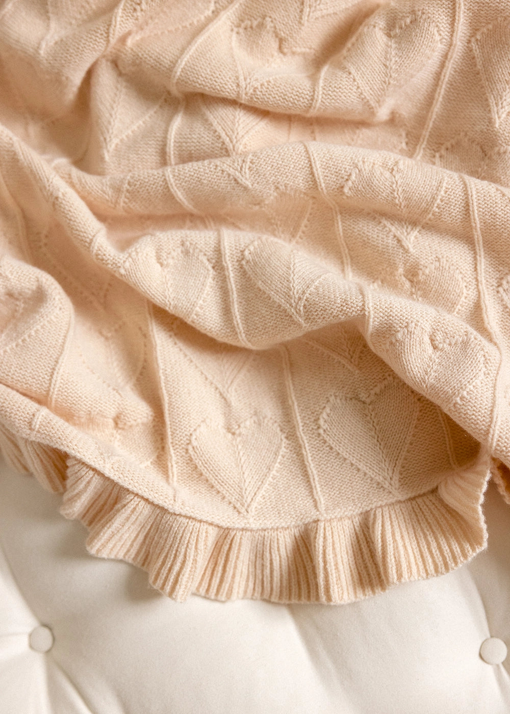 AU Baby Butter Cream Little Love blanket detail showing cable hearts and ruffled edge.