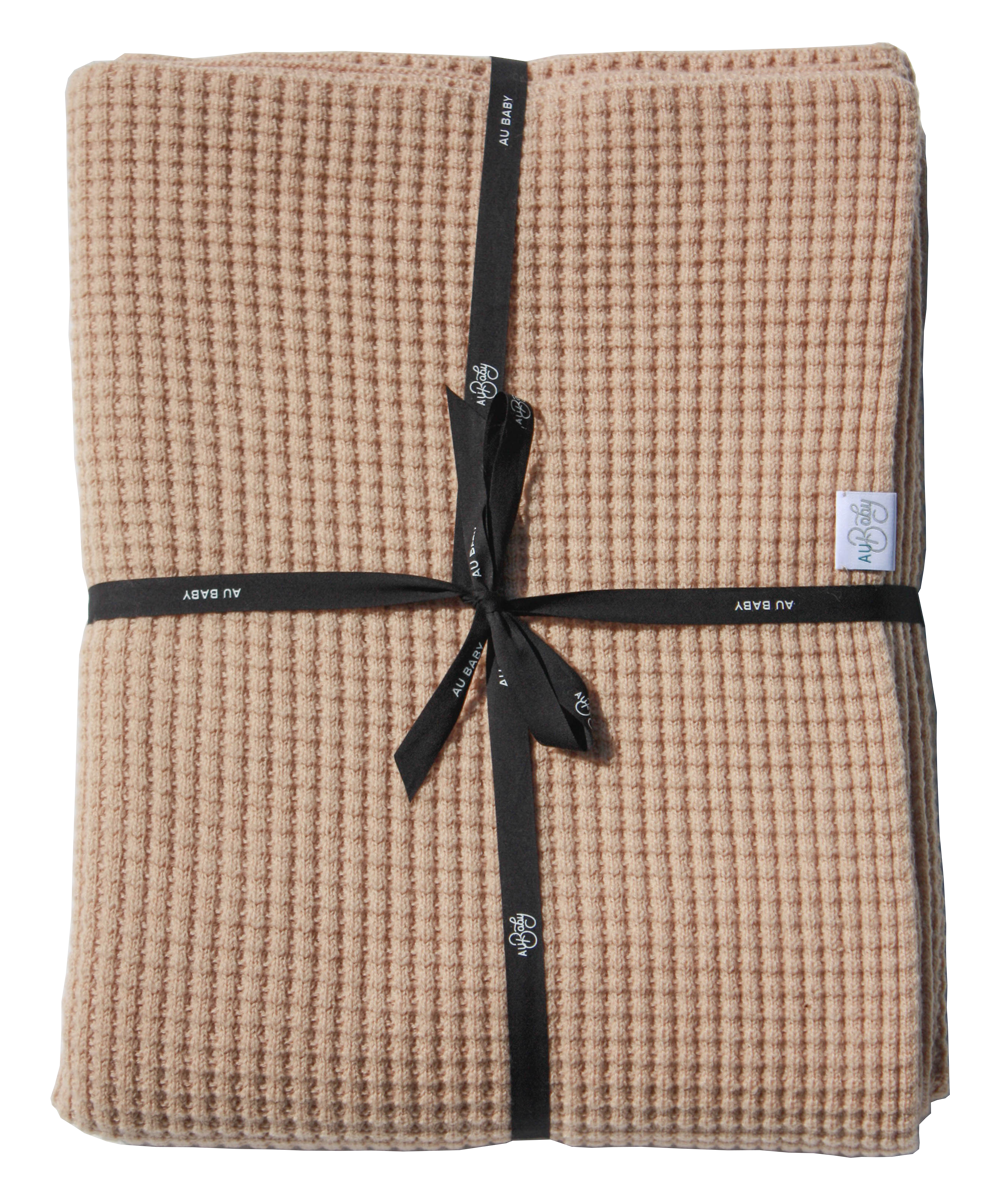 AU Baby Adult Popcorn blanket in Henna, folded and tied up with a black branded ribbon. A soft, cozy  100% plant dyed extrafine merino throw blanket.