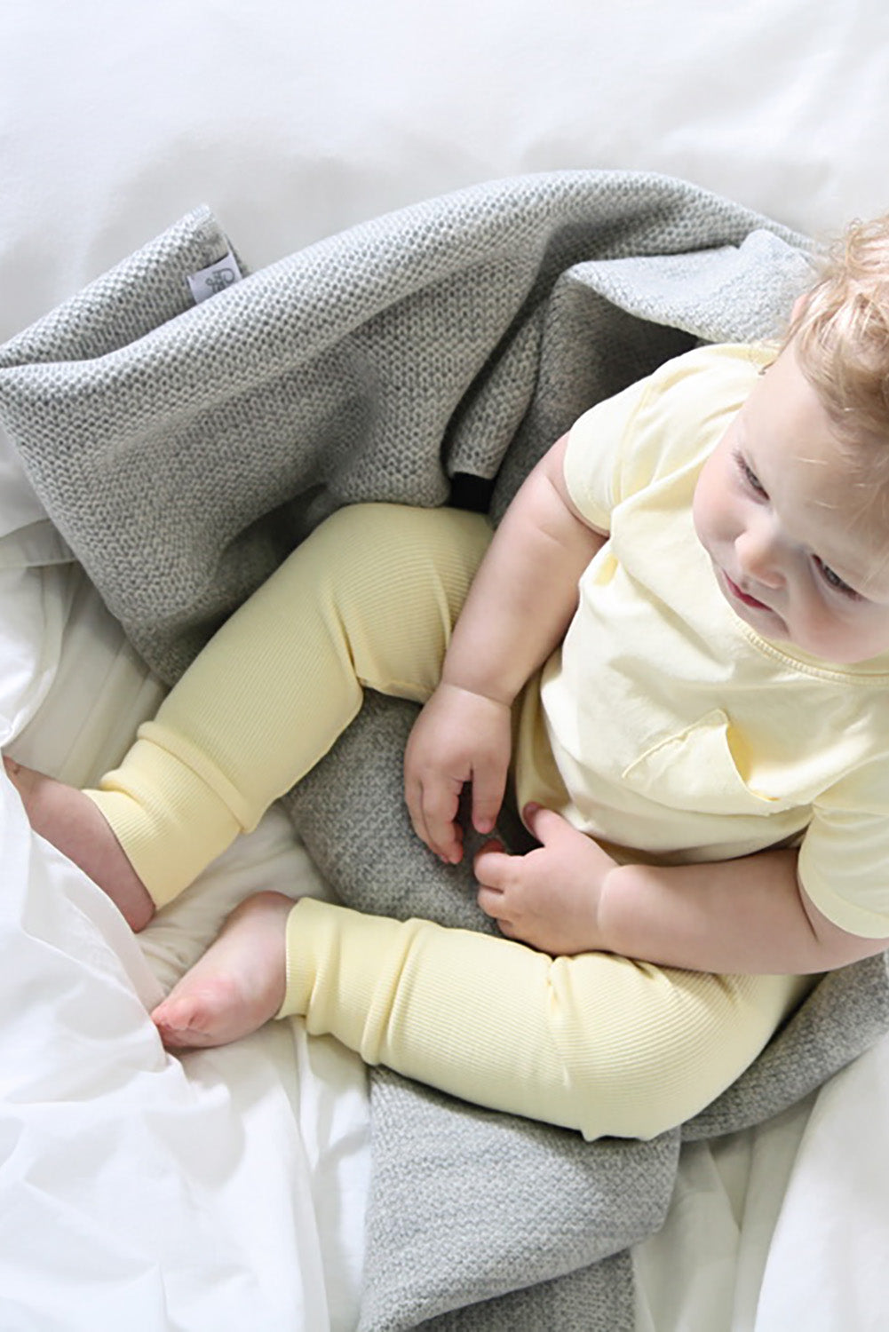 Toddler sitting on AU Baby heirloom merino baby blanket, naturally plant-dyed, personalization available, safe for eczema and sensitive skin, FSA/HSA eligible, luxury newborn gift