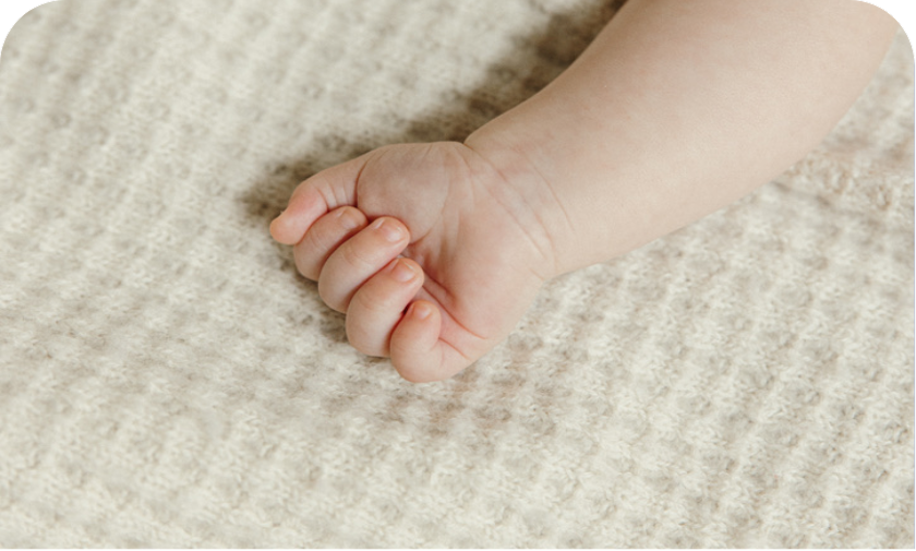 Baby hand resting on AU Baby merino wool blanket — hypoallergenic and safe for sensitive skin and eczema