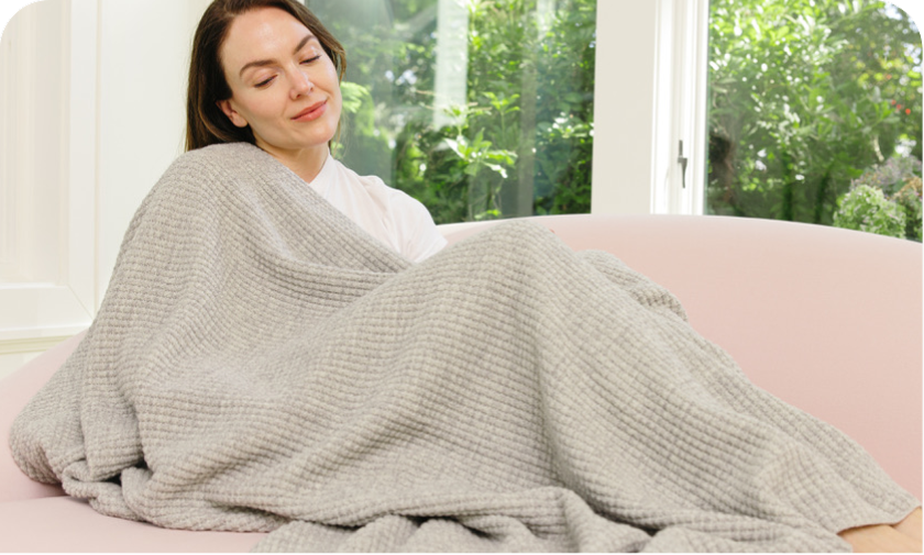 Woman wrapped in AU Baby adult merino wool blanket — naturally temperature regulating for deeper sleep