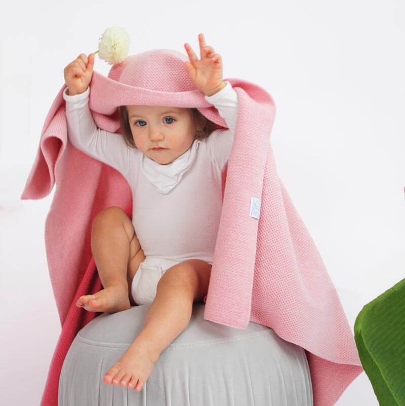 Little girl hiding under AU Baby Sawa blanket in Pink Quartz.